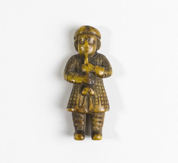 Carving, figure of a man playing pipes